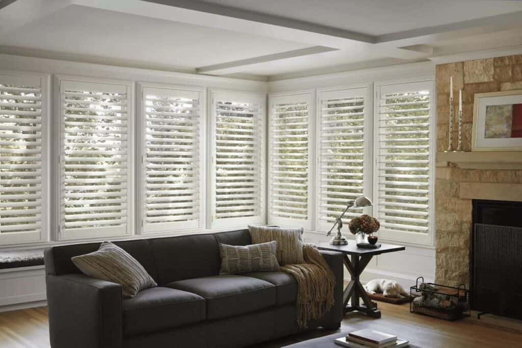 Bright room featuring elegant plantation shutters, comfortable sofa, and tasteful decor for a warm, inviting atmosphere.