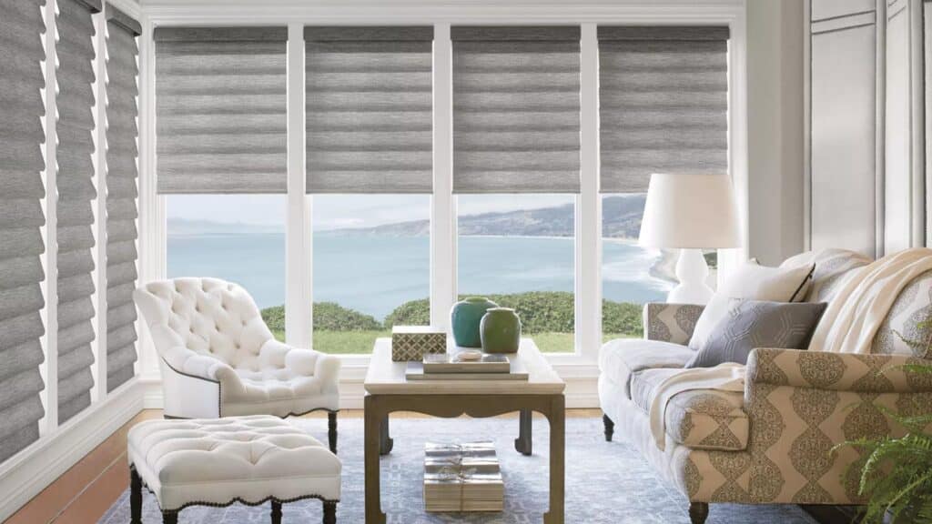 Bright living room with ocean vista, gray blinds, and elegant furniture.